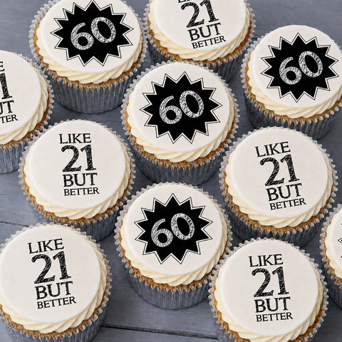 A close-up arrangement of frosted cupcakes topped with 60th birthday graphics. Several cupcakes have a black starburst design with the number 60 in white, while others read 'LIKE 21 BUT BETTER' in black text on white icing.