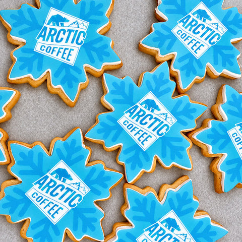 blue snowflake shaped biscuits with company logo for client gifts. Each snowflake has an iced design and branding. 