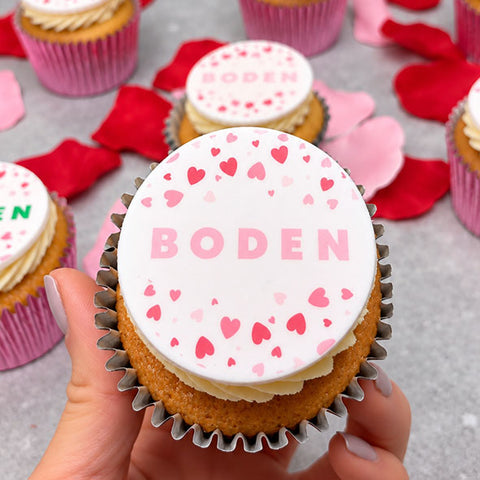 hand holding branded cupcake with valentines design of iced hearts and the Boden logo for a company event in London.