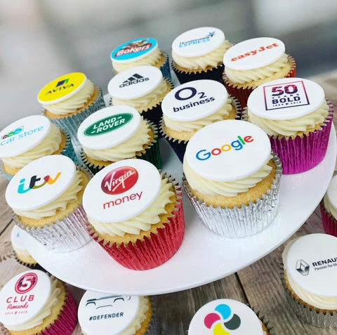 branded cupcakes with UK company logos printed onto edible icing discs. Showing brands like Virgin Money, Adidas, Land Rover and ITV. Available in gluten free and shown in a choice of case colours. 