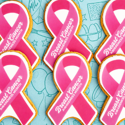 Pink breast cancer awareness ribbon-shaped biscuits with white lettering, saying "Breast Cancer awareness month"
