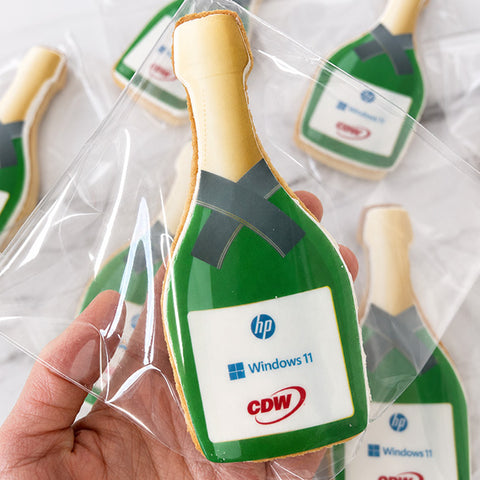 iced champagne bottle biscuit with company logos printed onto the icing for company celebration
