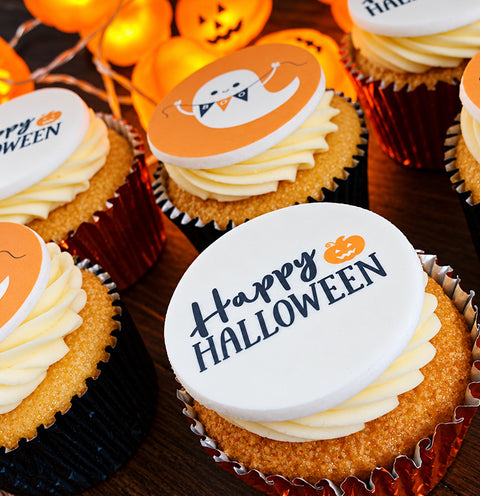 Halloween-themed cupcakes with toppers saying 'Happy HALLOWEEN' and another orange topper with a ghost illustration.