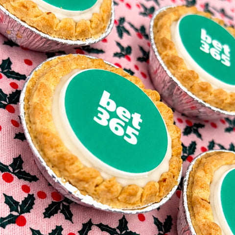 Mince pie with a printed logo topper on a festive holly tablecloth