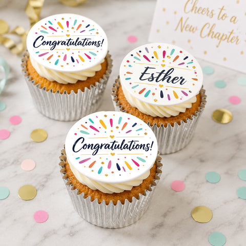 Personalised congratulations cupcakes  on a marble surface, each topped with a round icing decoration that reads Congratulations! 