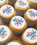 Thank you buttercream cupcakes with edible heart toppers on a wooden table
