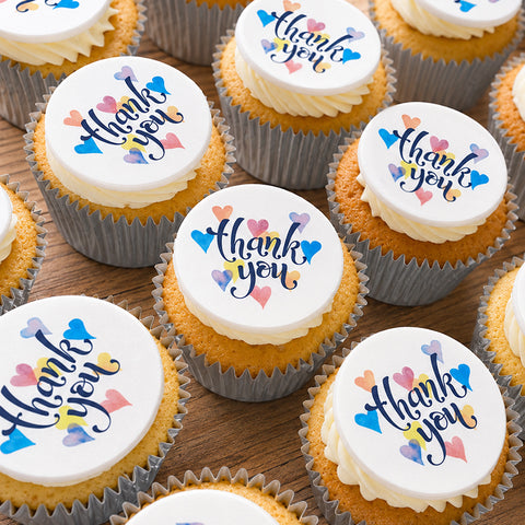 Thank you buttercream cupcakes with edible heart toppers on a wooden table