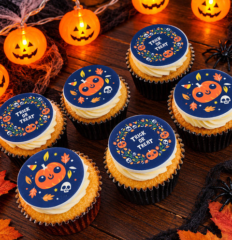 Trick or Treat Halloween cupcakes with pumpkin, skull and autumn leaf toppers on a dark wooden table